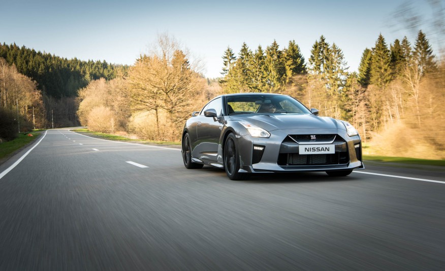 Grey 2017 Nissan GT-R driving on road with trees in background